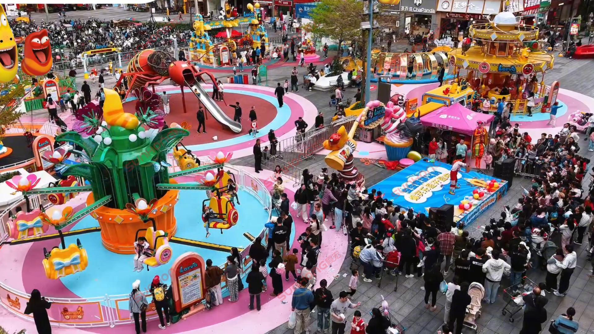 Crowds enjoy colorful rides and a stage show at the vibrant Larva Blooms outdoor theme park. Crowds enjoy colorful rides and a stage show at the vibrant Larva Blooms outdoor theme park.