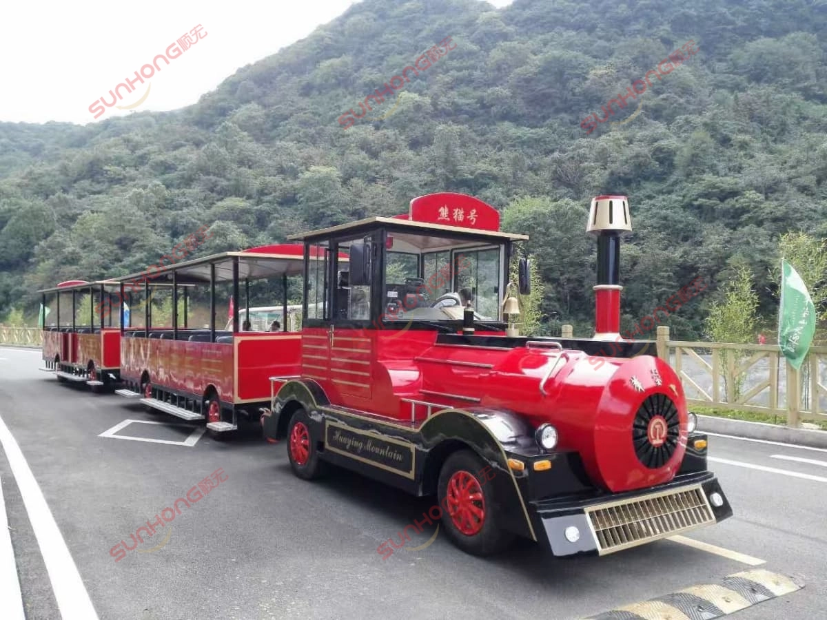 trem turístico-preto-vermelho-estrada-da-montanha - SUNHONG Trem turístico sem trilhos, vermelho e preto, circulando por uma estrada panorâmica nas montanhas - SUNHONG