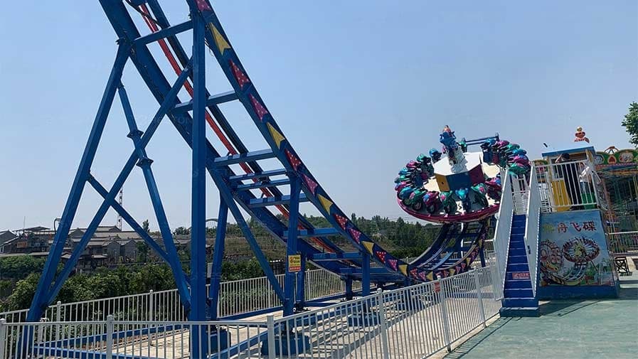 Amusement park ride with a rotating platform and winding blue track.