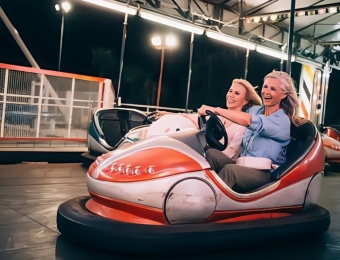 Duas mulheres sorridentes em um carrinho de bate-bate em um parque de diversões. - SUNHONG