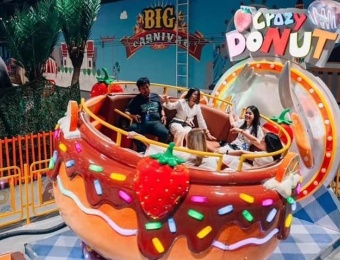 Pessoas rindo enquanto andam em um brinquedo giratório em formato de rosquinha, o Disco Tagada, um brinquedo de parque de diversões. - SUNHONG