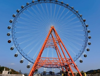 Uma roda-gigante gigante com base laranja contra um céu azul claro. - SUNHONG