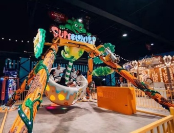 Atração de parque de diversões - Pêndulo dos Dinossauros com placa "SUPER GLORY" e pessoas em uma xícara giratória. - SUNHONG