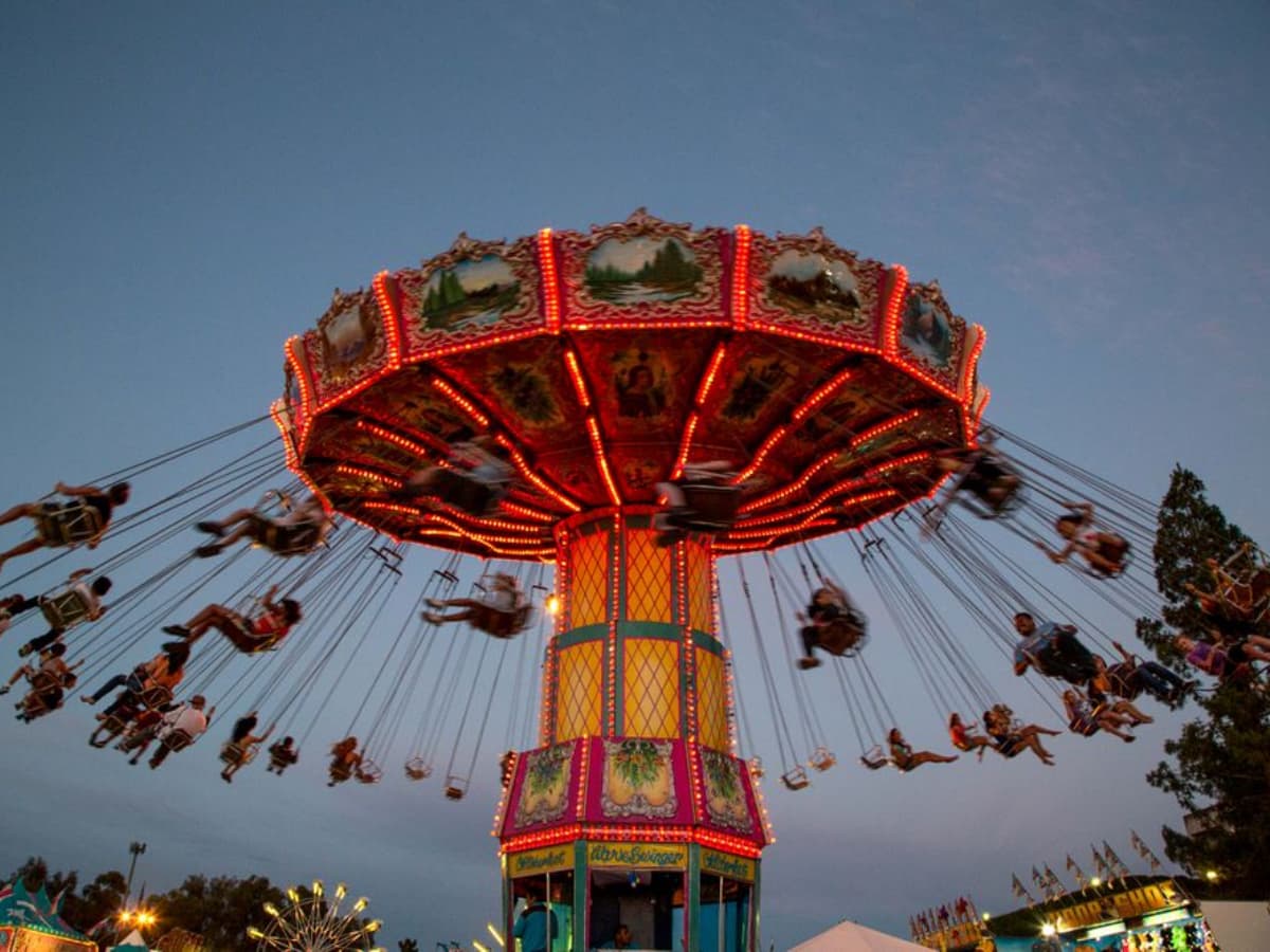Swing fairground ride in motion during twilight with riders enjoying the thrill.