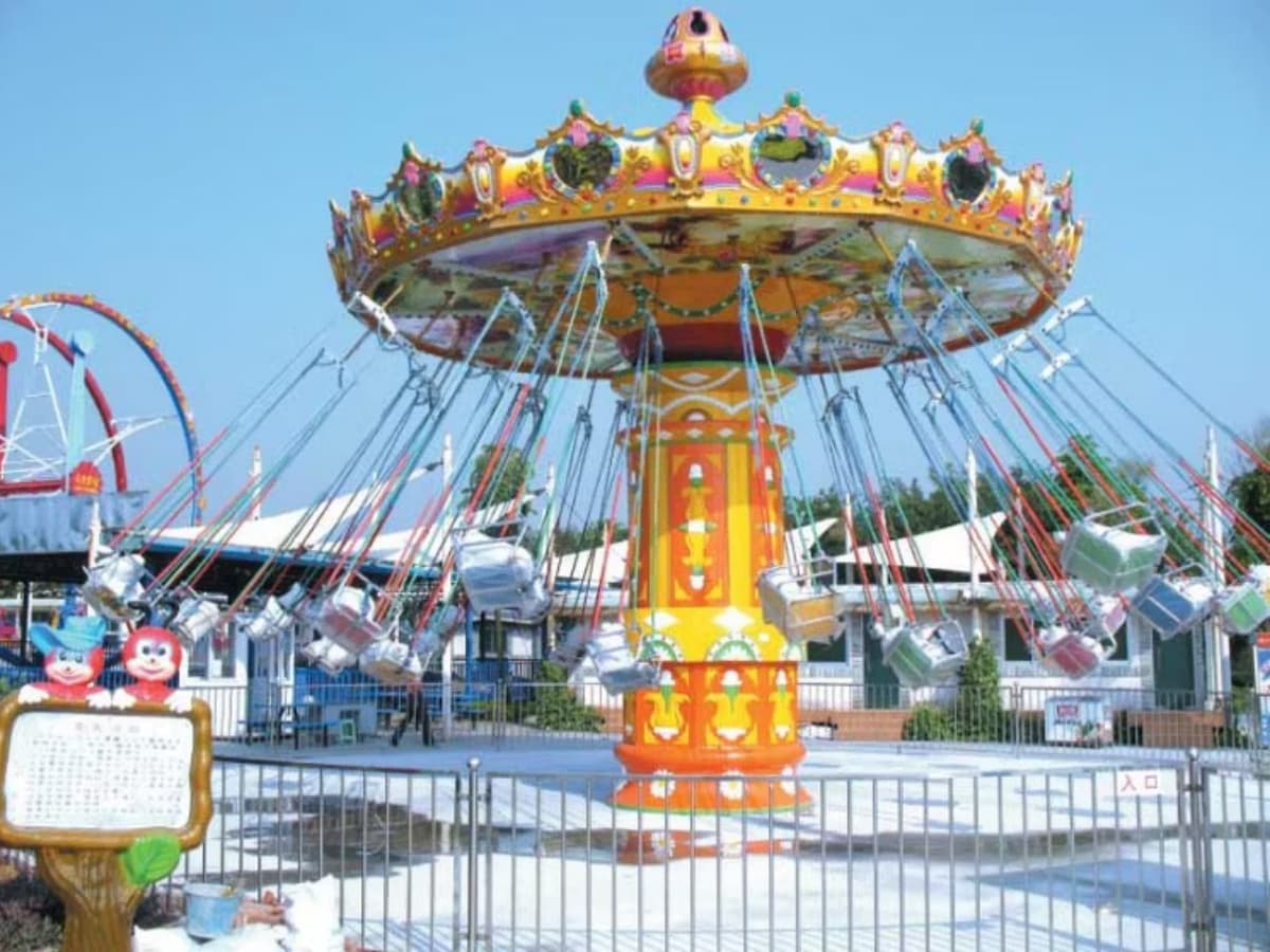 Colorful swing ride with cartoon-themed seats in a family amusement park.
