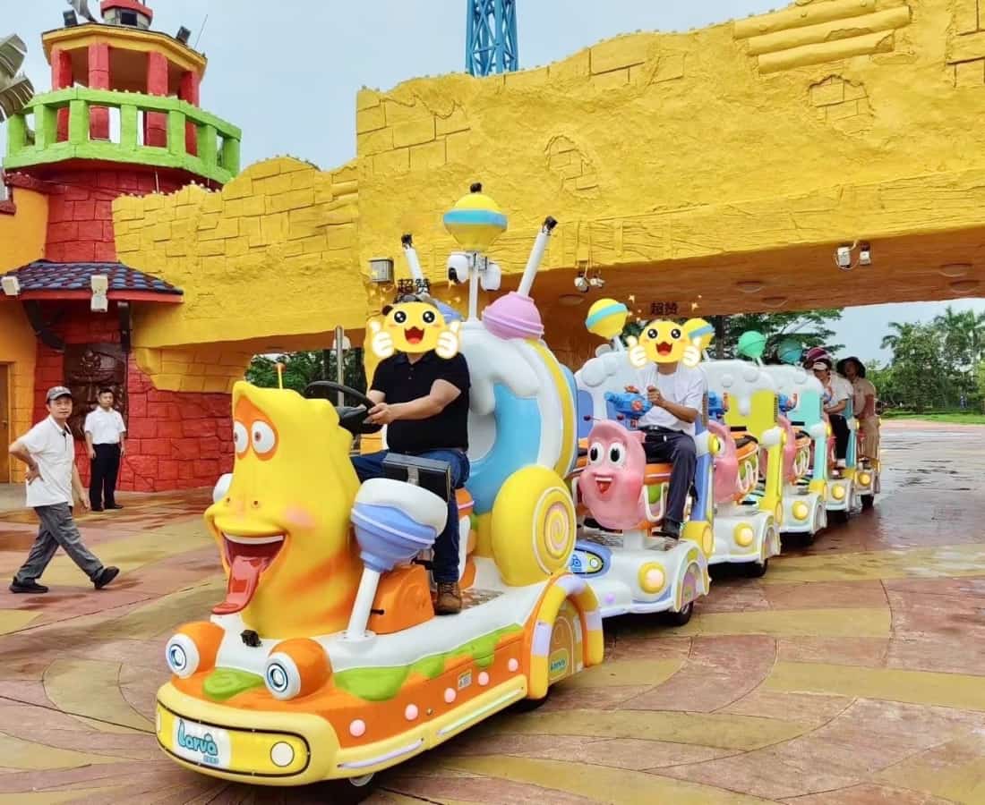 ركاب يستمتعون برحلة قطار SUNHONG الترفيهي ذي الطابع اليرقي، وهو قطار مخصص بدون قضبان مصمم خصيصًا لمدن الملاهي والمنتزهات الترفيهية وأماكن الترفيه العائلي - SUNHONG