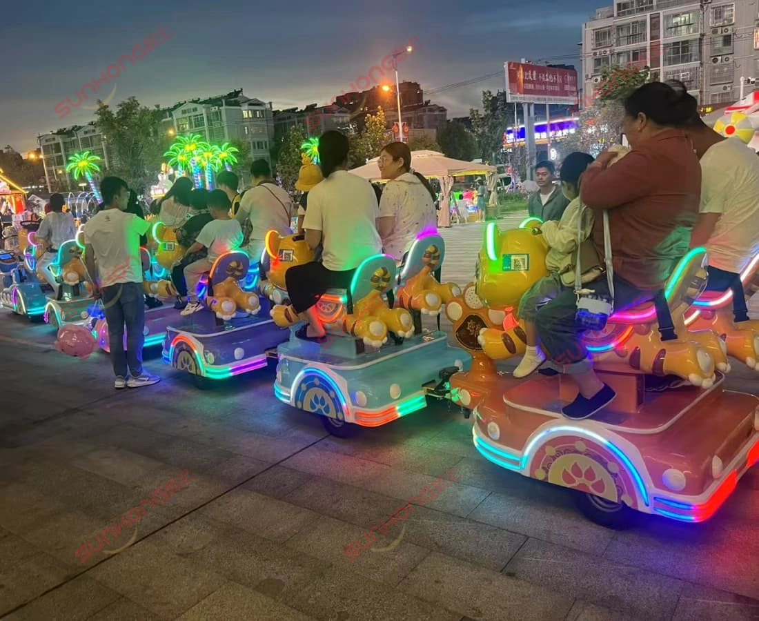 tigger-small-train-rides-outdoor-evening-busy - SUNHONG Back view of Tigger small train ride carrying parents and kids during a busy outdoor evening event. - SUNHONG