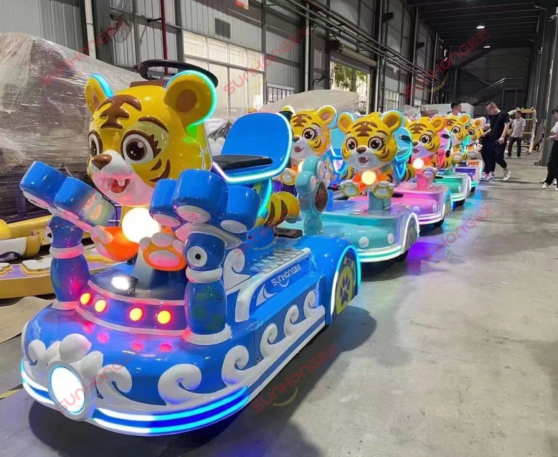 tigger-small-train-rides-production-line-indoors - SUNHONG Tigger trackless trains assembled and displayed inside the factory, showing fiberglass finish and vibrant lights. - SUNHONG