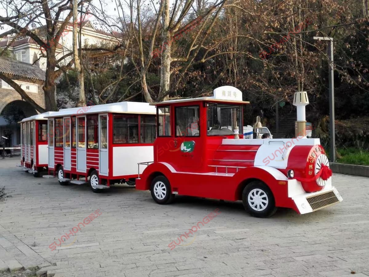 Tren turístico sin vías, rojo y blanco, en el casco antiguo Paseo en tren turístico rojo y blanco sin vías en una pintoresca zona turística del casco antiguo