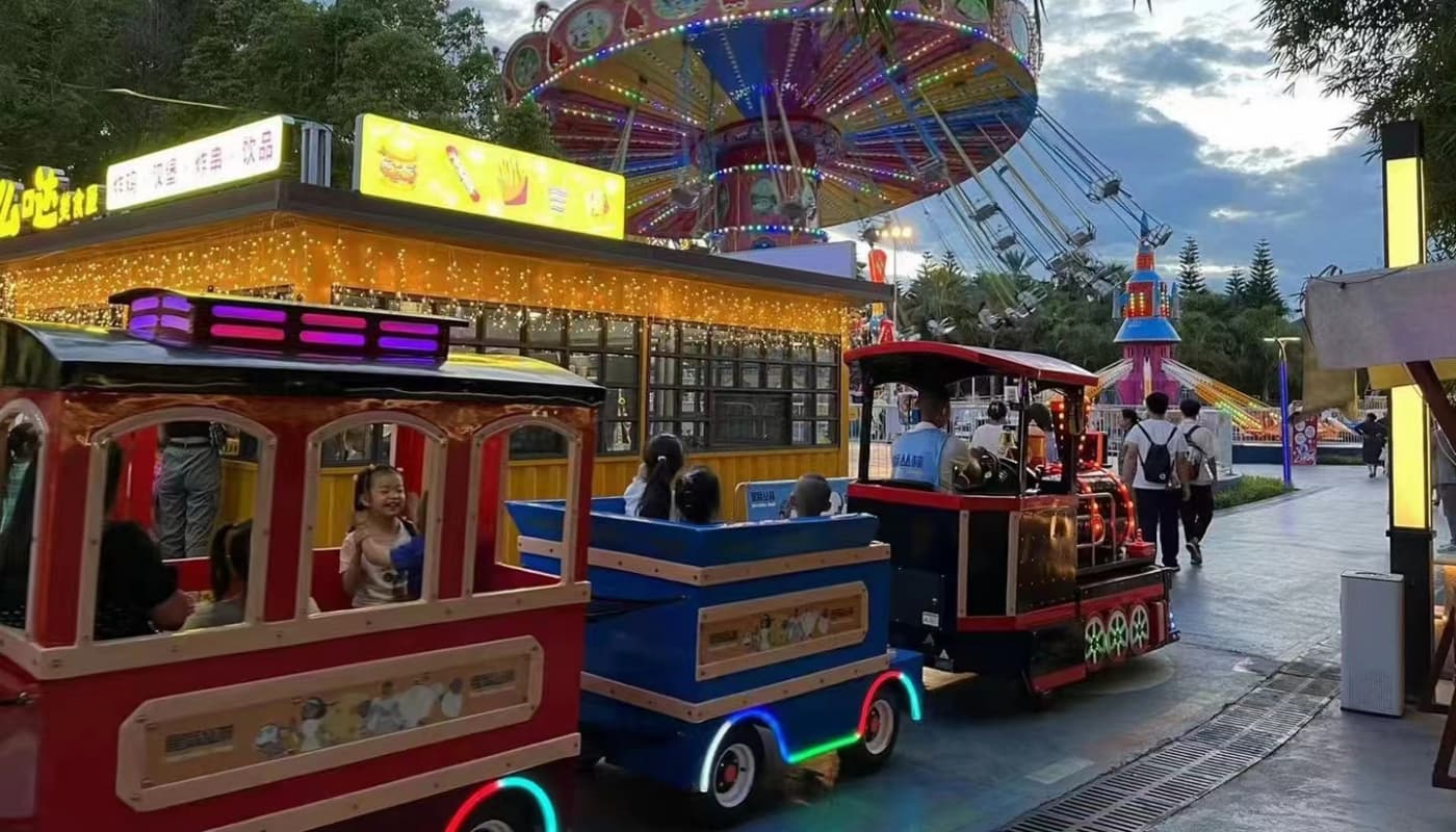 Train sans rails royal circulant dans un parc à thème la nuit, éclairé par des lumières LED – exemple d&#39;un train sans rails construit