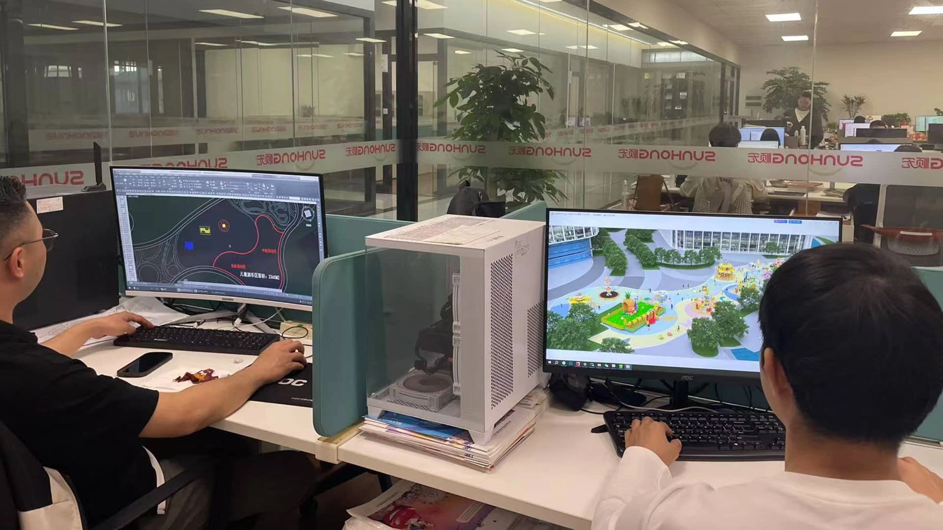 Two engineers from SUNHONG are sitting in front of their computers designing a 3D model of the amusement park. - SUNHONG