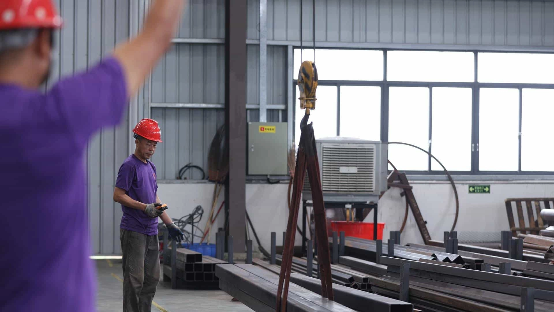 Dos trabajadores de SUNHONG dirigen el transporte de acero.