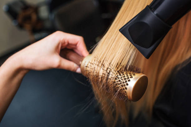 Stylist blow-drying blonde hair with a round brush.  Perfect for private label salon products.