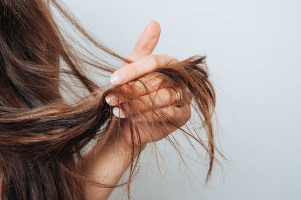 Here's an alt text option:

Woman's hand showing damaged hair.  Wholesale hair care products can help.