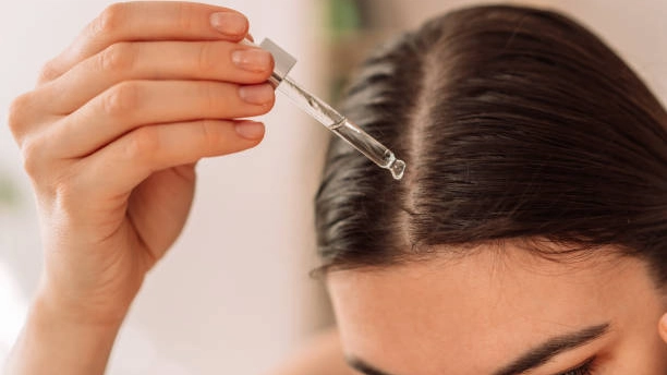 Woman applying professional hair oil to scalp.