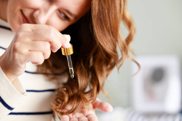 Woman applying wholesale hair growth oil to her curly hair.