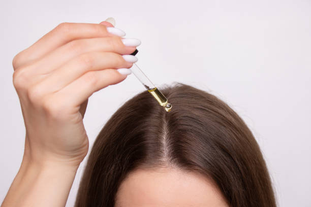 Woman applying professional hair supplies serum to scalp.