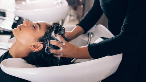 Aroma guru hair serum application: A stylist gently washes a client's hair with a luxurious lather.