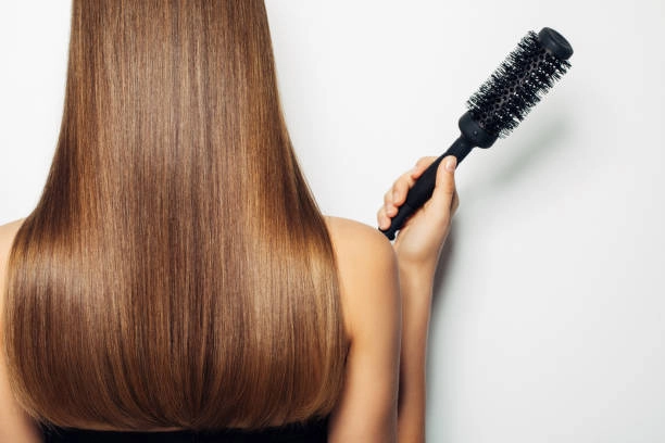 Here's an alt text option for the image:

Healthy long hair, held next to a round brush. Wholesale natural hair care products.