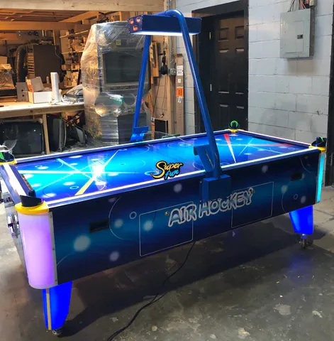 Illuminated air hockey table with a blue cosmic design and overhead scorer. Illuminated air hockey table with a blue cosmic design and overhead scorer.