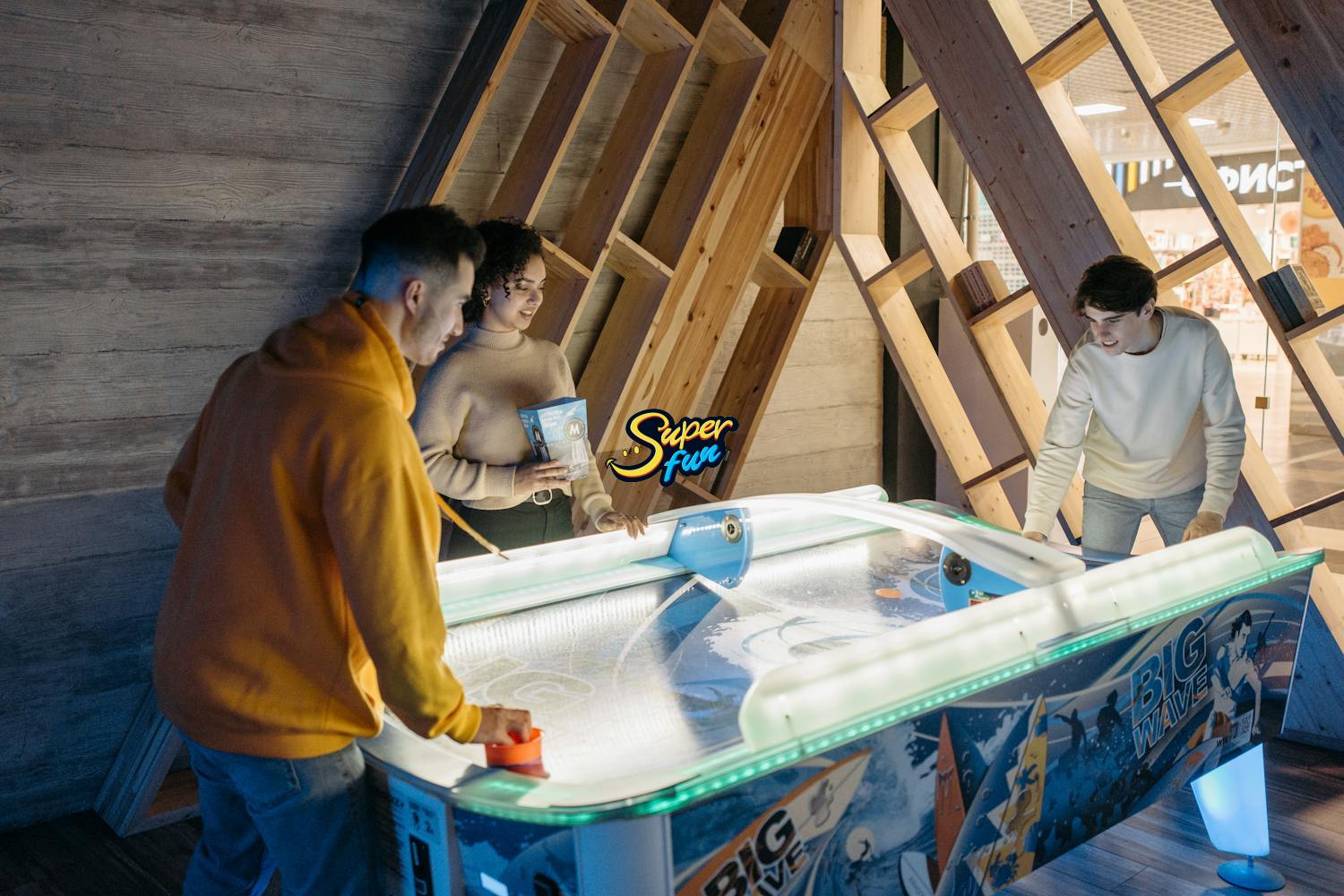 Three young adults playing air hockey indoors Three young adults playing air hockey indoors