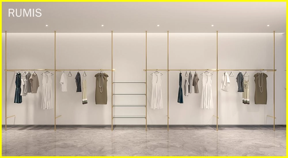 FLEEK custom retail clothing displays: Elegant gold clothing racks showcasing apparel in a modern retail space. - RUMIS