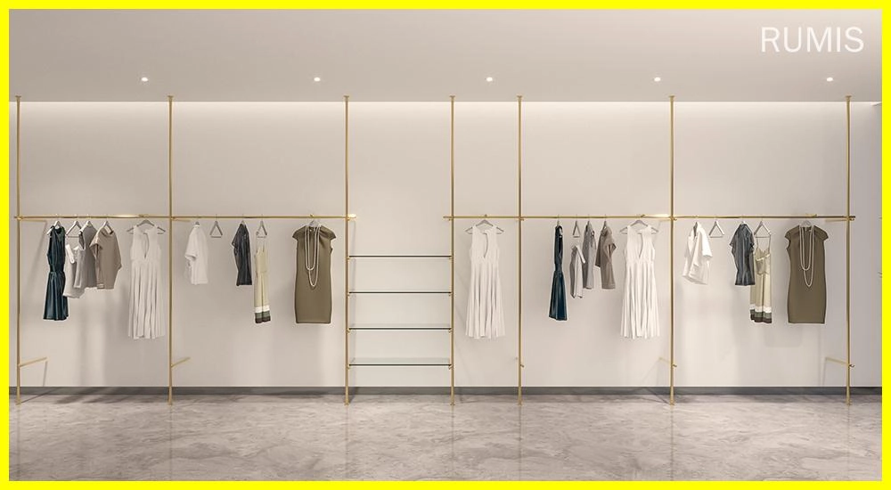 FLEEK custom retail clothing displays: Elegant gold clothing racks showcasing apparel in a modern retail space. - RUMIS