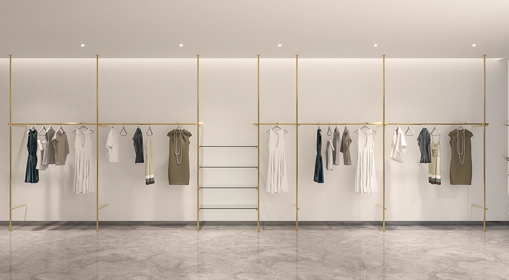 FLEEK custom retail clothing displays: Elegant gold clothing racks showcasing apparel in a modern retail space.