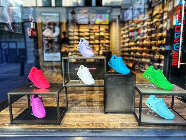 Colorful sneakers arranged on shelves to display shoes in a retail store window.