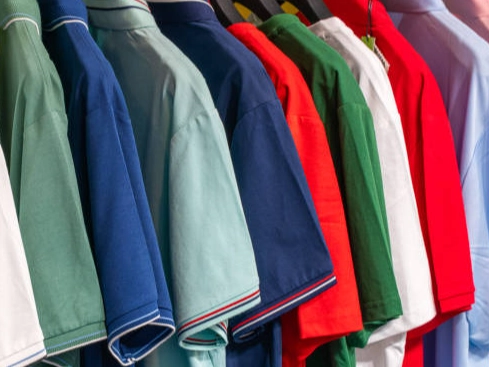 Colorful shirts on a clothing rack with shelves.