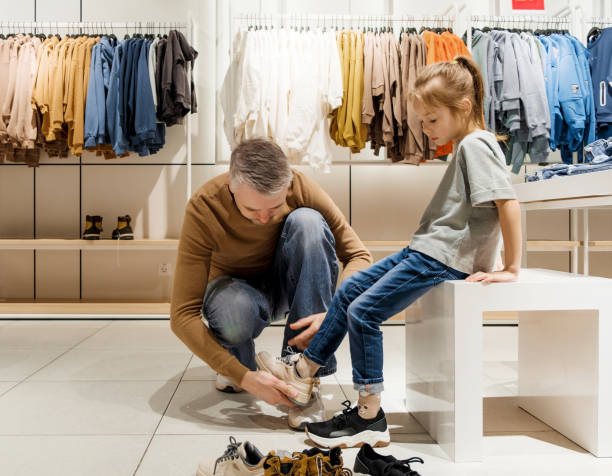 Dad helps child choose shoes from shoe display fixtures.