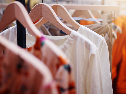 T-shirt display frame with clothing on wooden hangers.