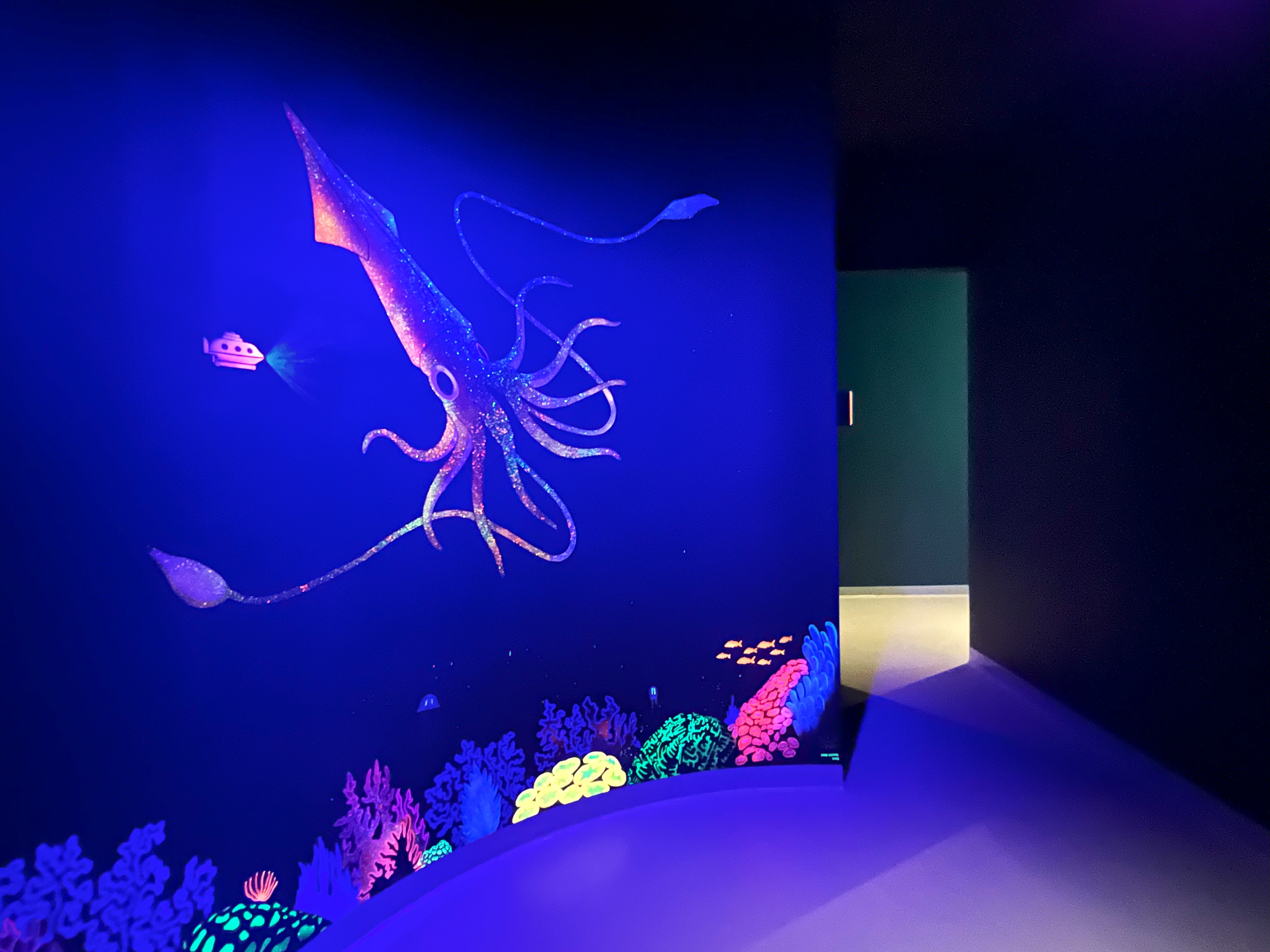 Glowing squid and coral on an interactive wall projection.