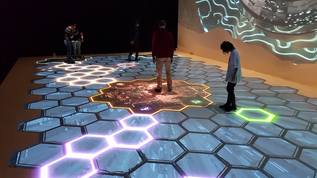 People interacting with an interactive hexagonal tile floor projection.