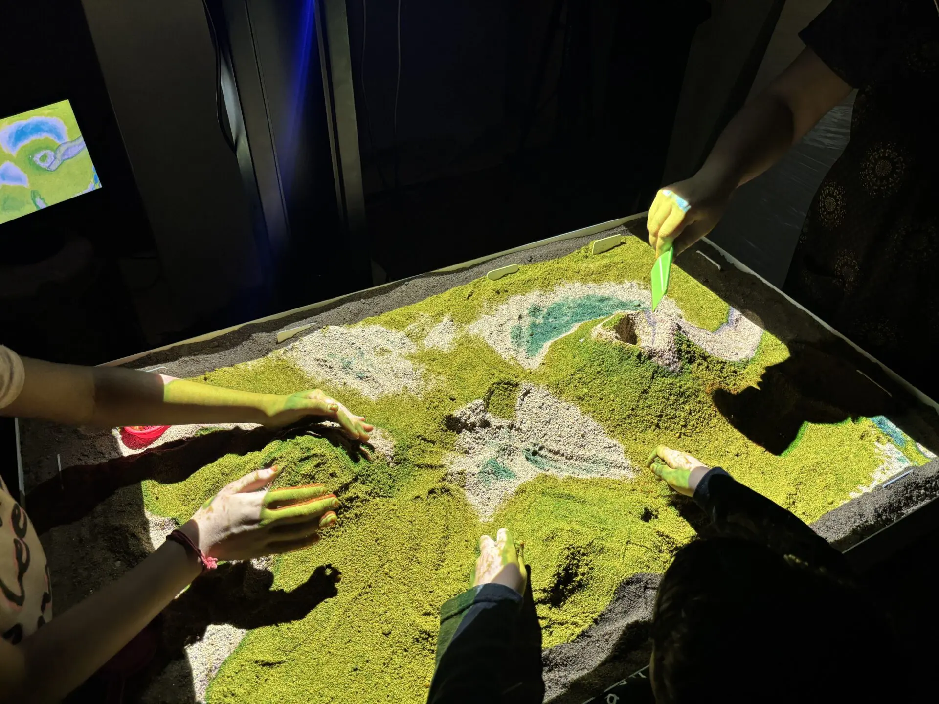 People interacting with an interactive topographic sandbox.