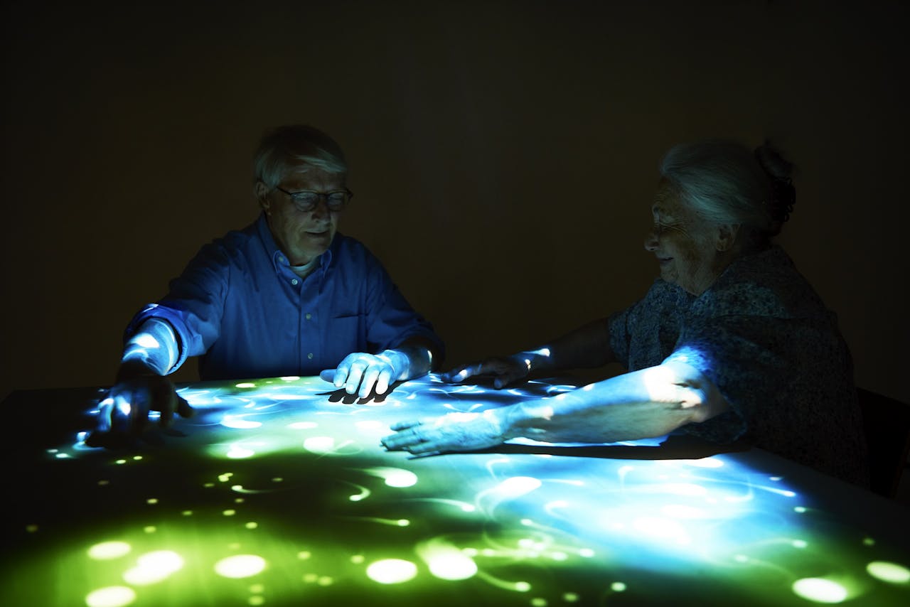 Seniors enjoy interactive projection games on table.