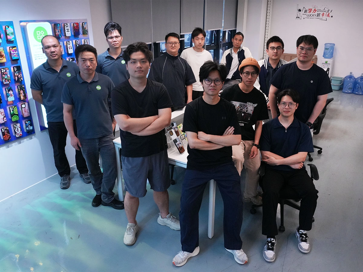 A group of men posing in a mobile phone accessory shop or office. - KeMore