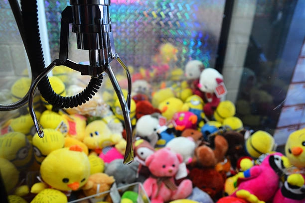 Claw machine filled with stuffed animals, mostly yellow chicks and pink teddy bears.