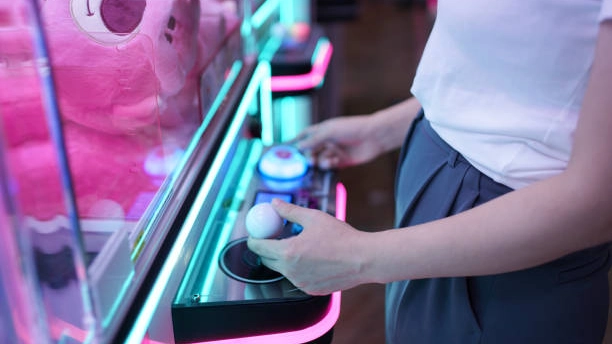 Woman playing prize machines; winning a plush toy.