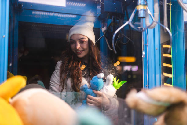 Woman at site of a claw machine, holding plush toys.