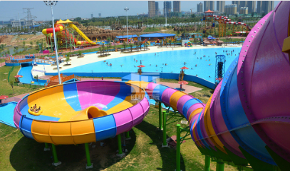 Colorful water park with large slides, a wave pool, and many people enjoying the rides.