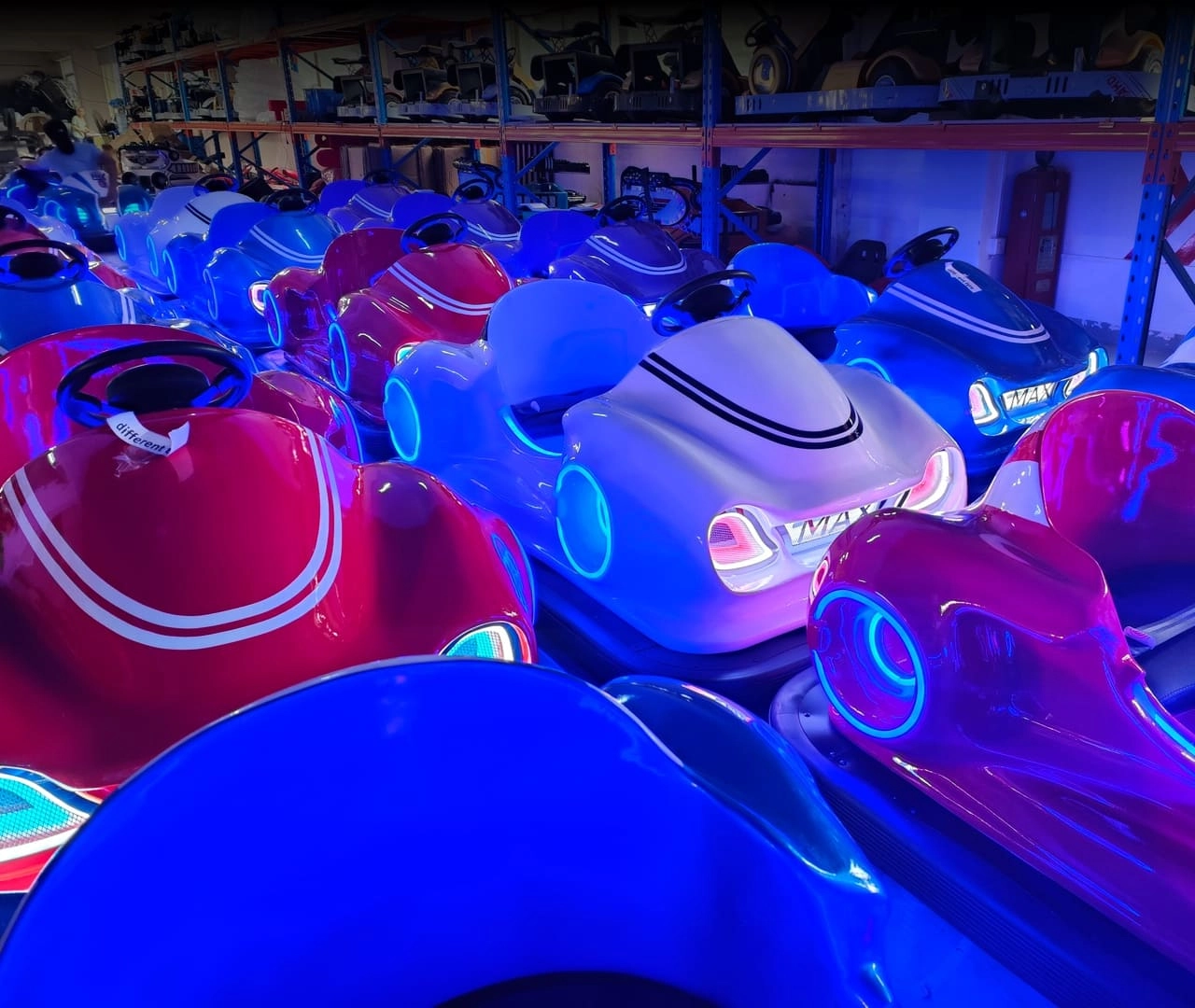 A row of colorful bumper cars with blue and white lights.