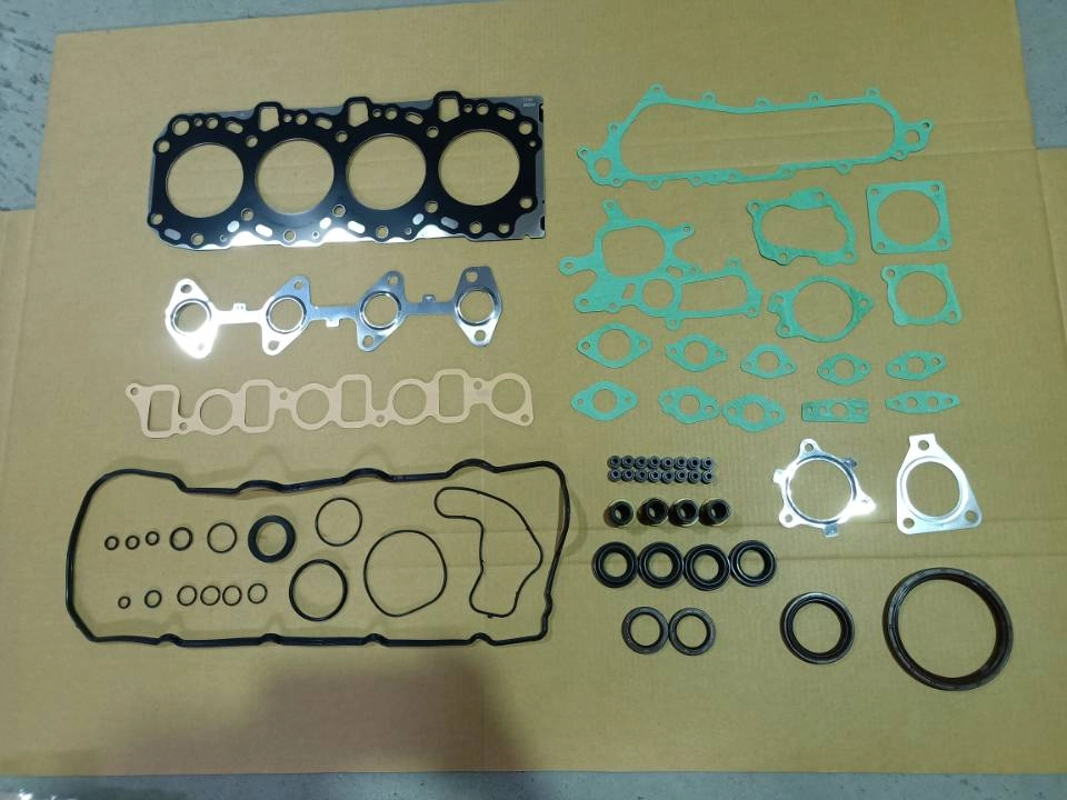 Engine rebuild kit with gaskets, seals, and hardware laid out on cardboard.