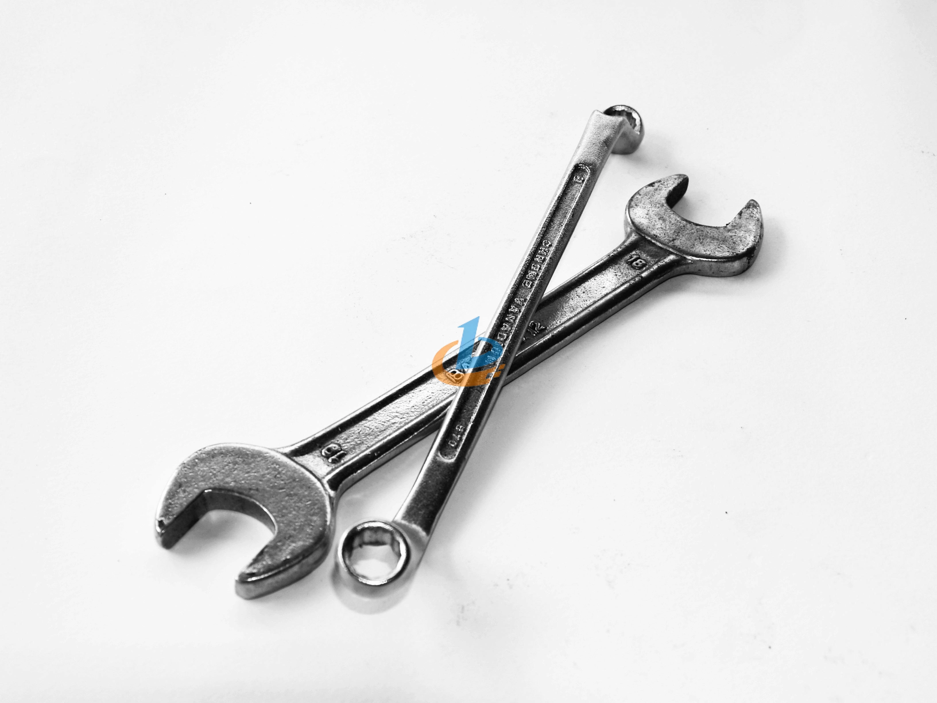 A-pair-of-crossed-metal-wrenches-on-a-clean-white-surface. A pair of crossed metal wrenches on a clean white surface.