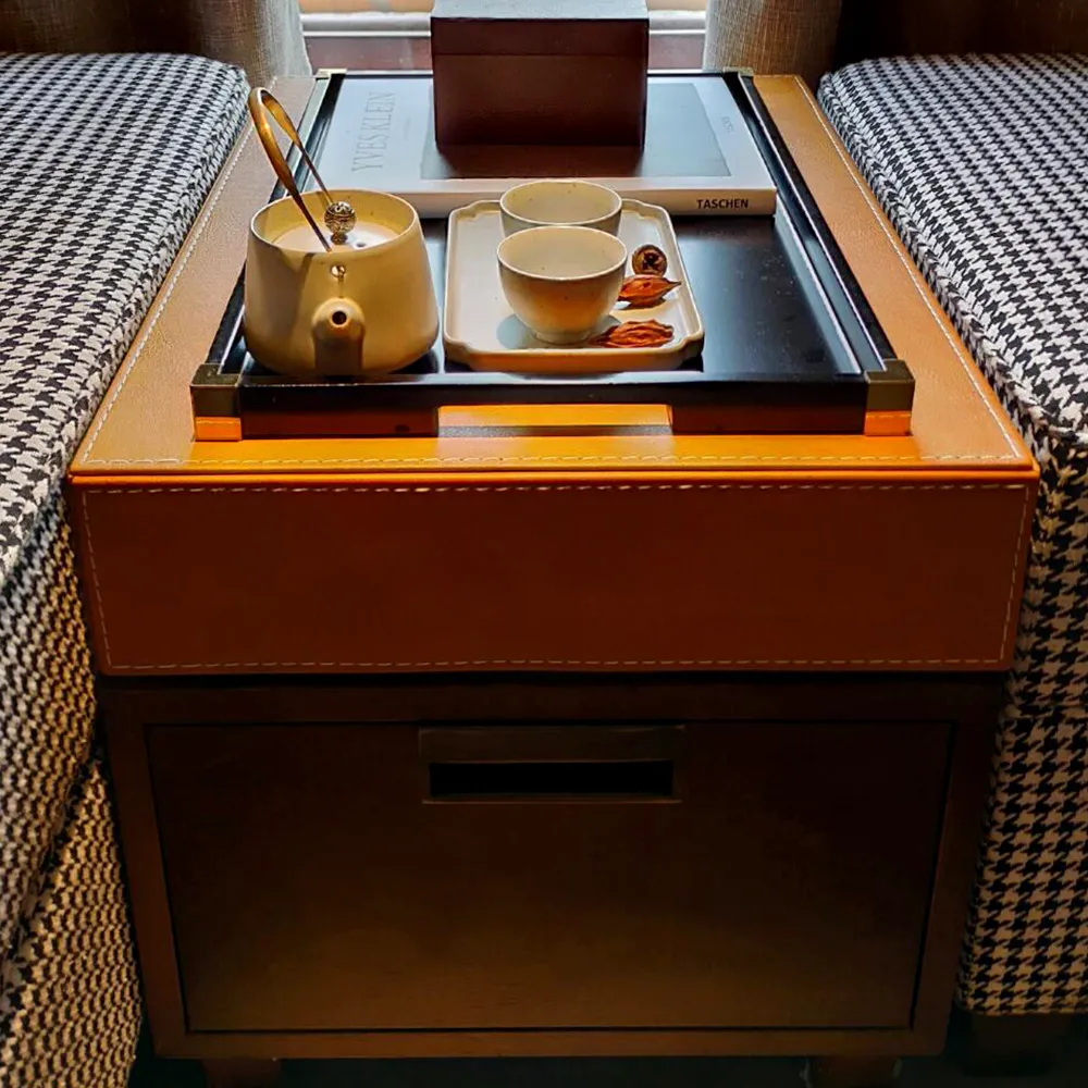 Custom leather-topped side table with tray, tea set, and hidden drawer &mdash; designed for luxury hotel guestroom comfort.