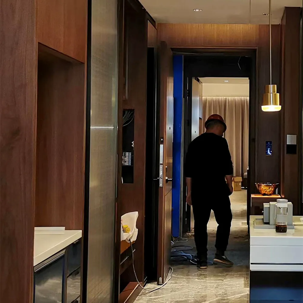 On-site installation of luxury hotel suite &mdash; craftsman walking through hallway with built-in wood paneling and concealed lighting.