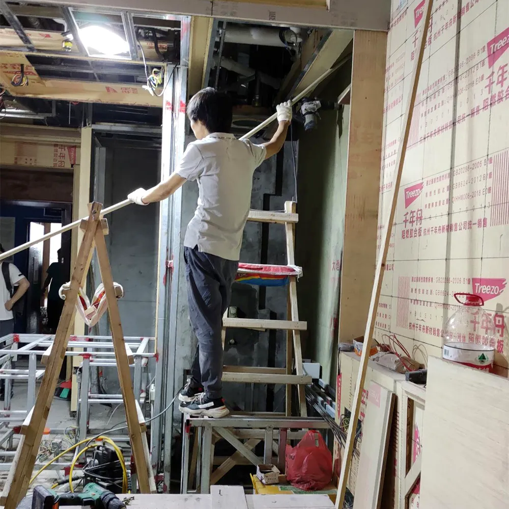 Craftsman installing ceiling framework and integrated lighting during luxury hotel guestroom construction phase.