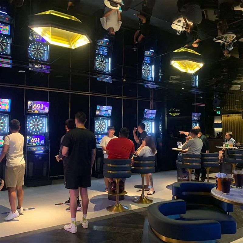 People playing darts at a modern, upscale bar with mirrored ceilings and gold accents.