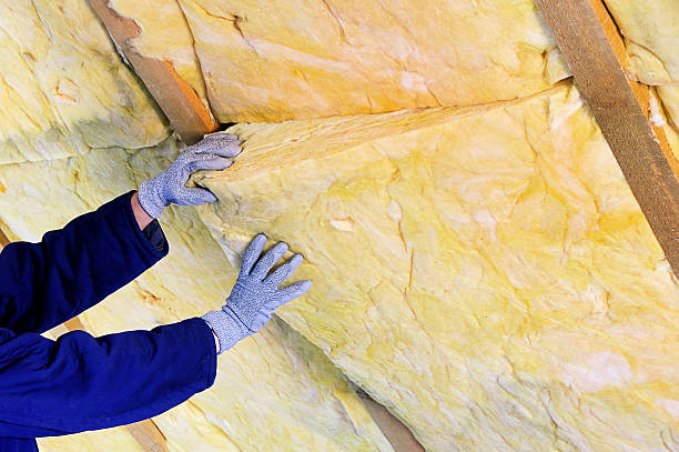 Hands installing yellow rock wool insulation.