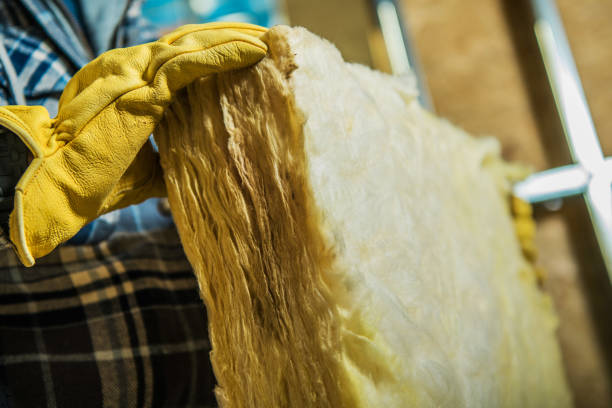 Close-up of a worker holding wall heat insulation material.  The material is light yellow and fibrous.